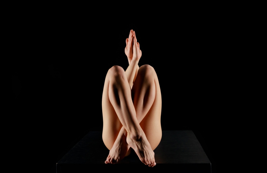 young woman with crossed legs practicing yoga isolated on black