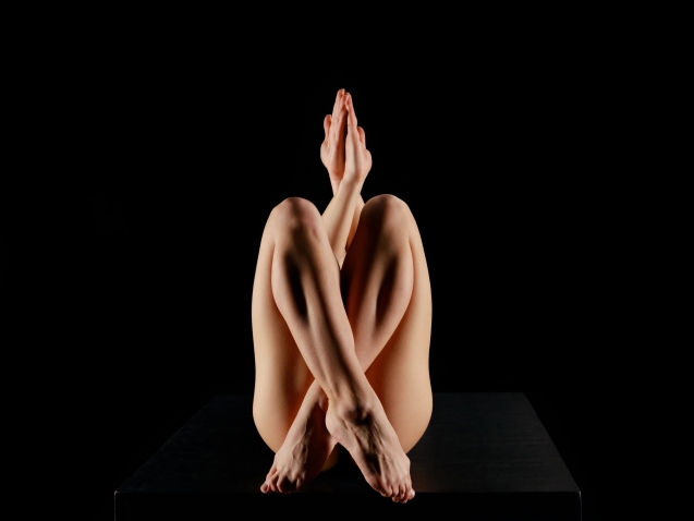 young woman with crossed legs practicing yoga isolated on black