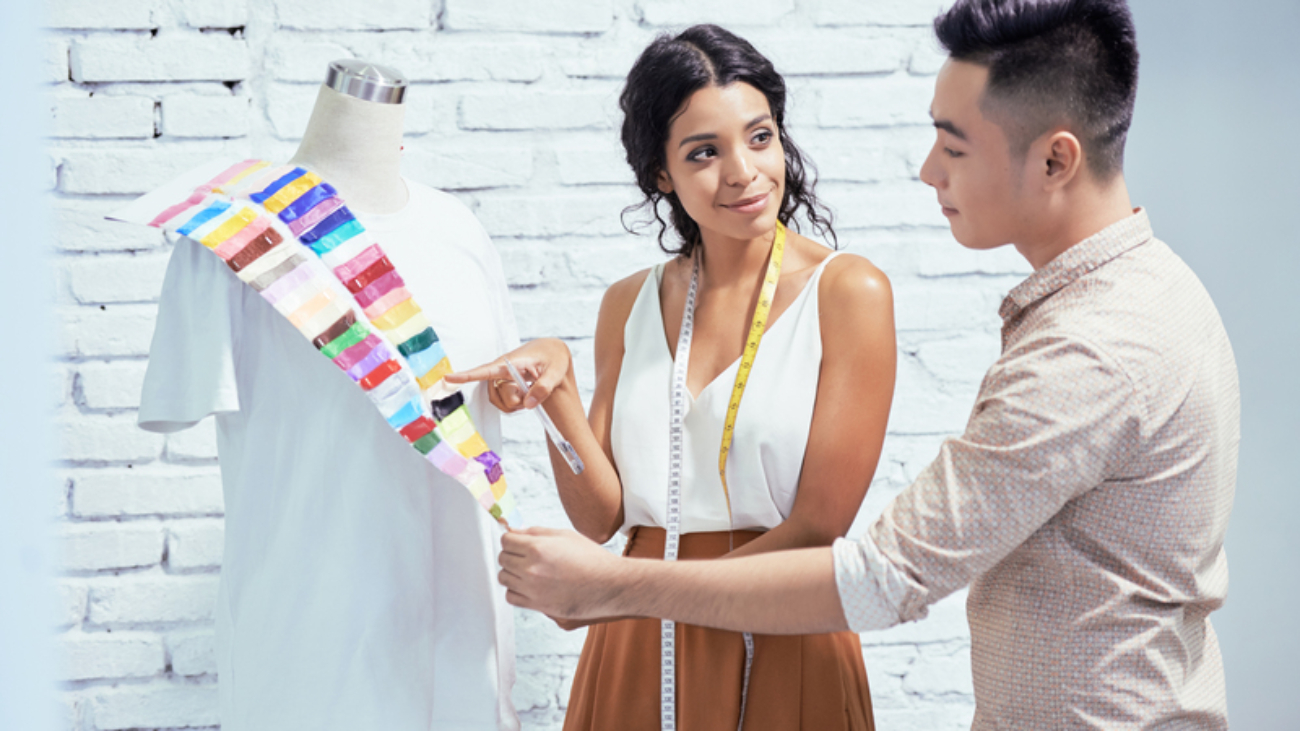 Young female designer suggesting to choose a color for the shirt to her client in studio