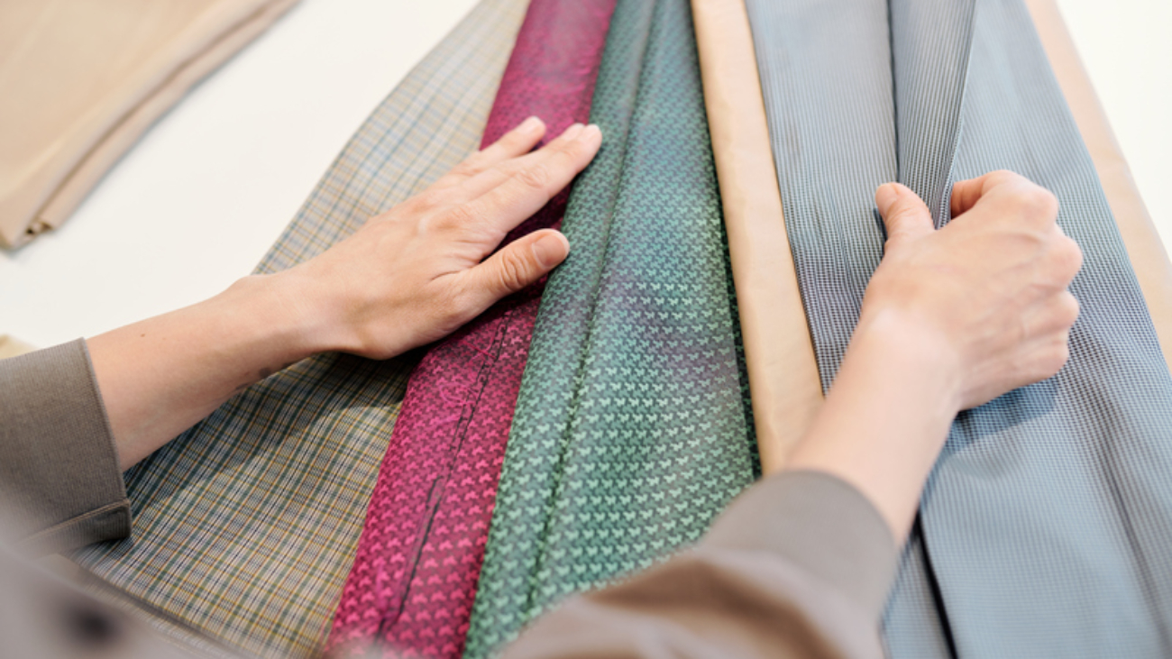 Female designer choosing suitable color and texture of fabric while looking through textiles for new collection