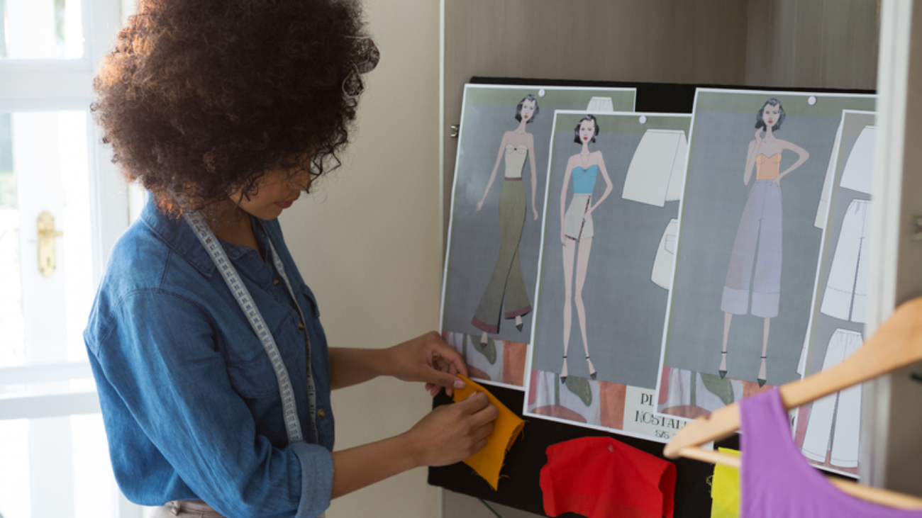 Female fashion designer attaching fabric on bulletin board at home