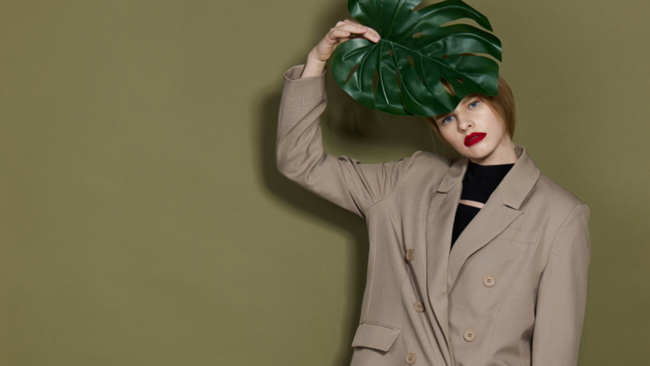 portrait of a woman in coat red lips fashion palm leaf isolated background. High quality photo